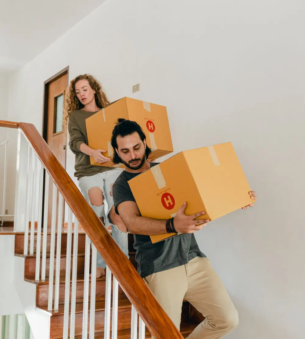 Casal carregando caixas de mudança pela escada